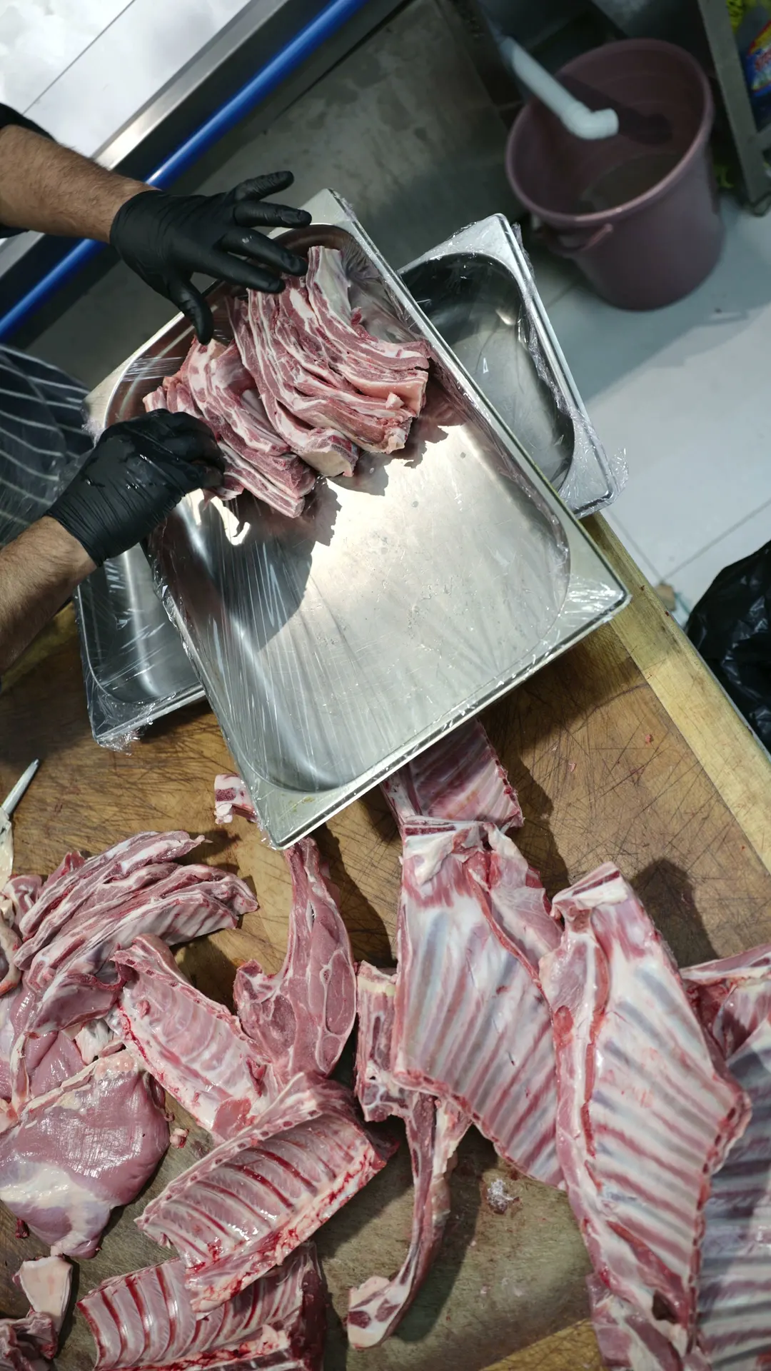 Lamb ribs and chops being laid out at the halal butcher counter