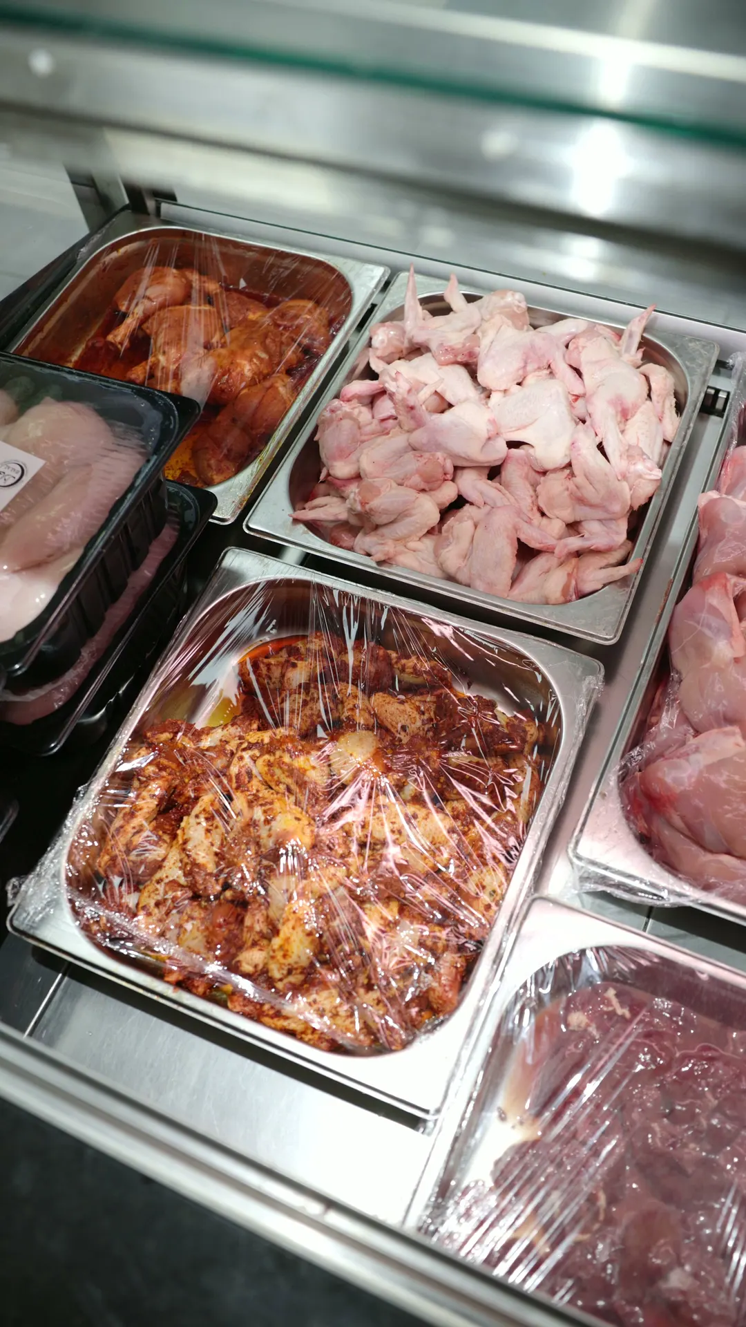 Trays of marinated chicken, diced chicken and fresh meat in the counter